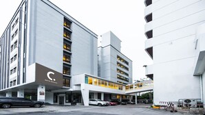 Een modern hotel met een opvallend 'C'-logo, meerdere verdiepingen en een overdekte parkeerplaats.