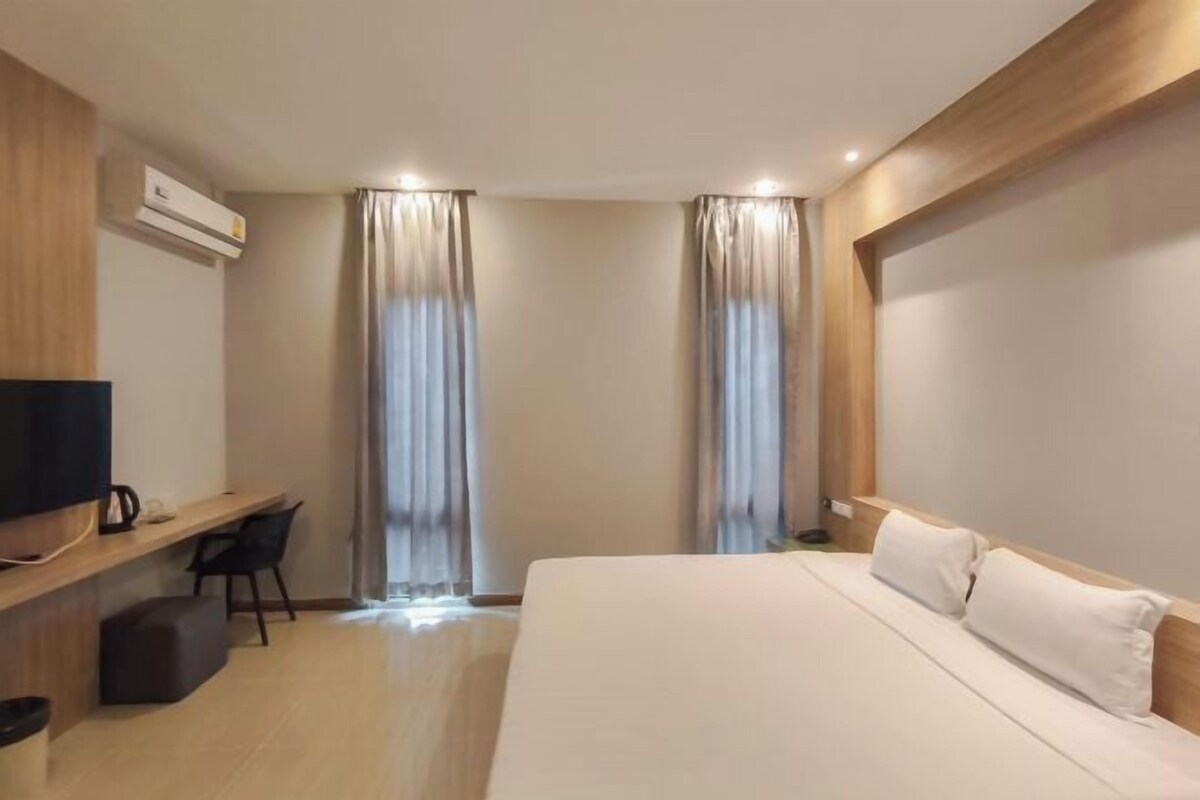 A modern hotel room with a large bed, a desk with a chair, and a TV.