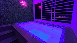 A spa area with a hot tub, a neon sign, and a window with blinds. - Charming Getaway in the Heart of Baní – Private Jacuzzi Included! (Baní)