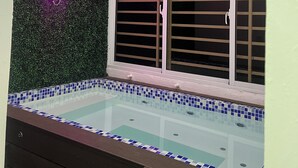 A spa area with a neon sign, a window with blinds, and a tiled pool. - Charming Getaway in the Heart of Baní – Private Jacuzzi Included! (Baní)
