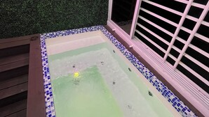 A spa area with a hot tub, a neon sign, and a window with blinds. - Charming Getaway in the Heart of Baní – Private Jacuzzi Included! (Baní)