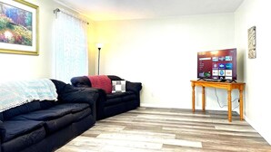 A living room with a black sofa, a wooden coffee table, and a flat-screen TV on a stand. - Emerald - GREAT PARK, 3br, Yard, Pet-Friendly (Paulding)