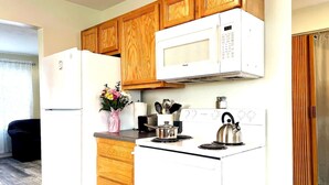 A compact kitchen with wooden cabinets, a white refrigerator, a microwave, a stove, and a kettle. - Emerald - GREAT PARK, 3br, Yard, Pet-Friendly (Paulding)