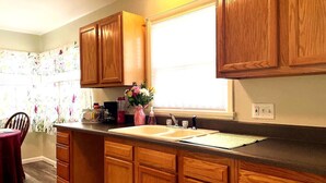 A kitchen with wooden cabinets, a double sink, and a window with blinds. - Emerald - GREAT PARK, 3br, Yard, Pet-Friendly (Paulding)