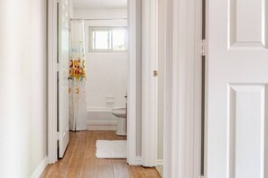 Un pasillo estrecho que conduce a un baño con inodoro y bañera.