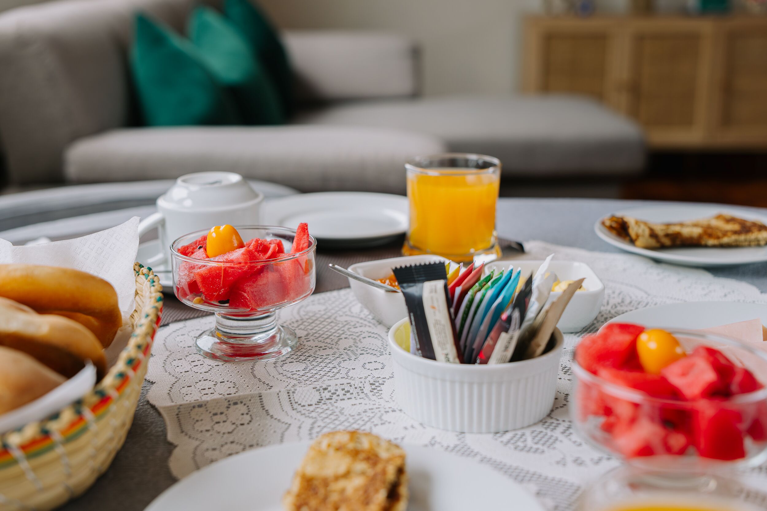 Una escena de desayuno con diversos alimentos y un vaso de jugo de naranja sobre una mesa.