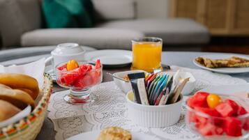 Una escena de desayuno con diversos alimentos y un vaso de jugo de naranja sobre una mesa.
