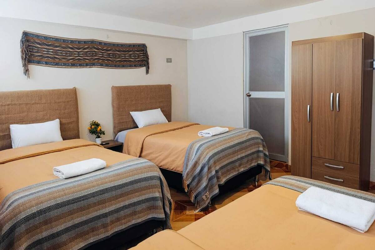 A hotel room with two beds, a wardrobe, and a decorative wall hanging.
