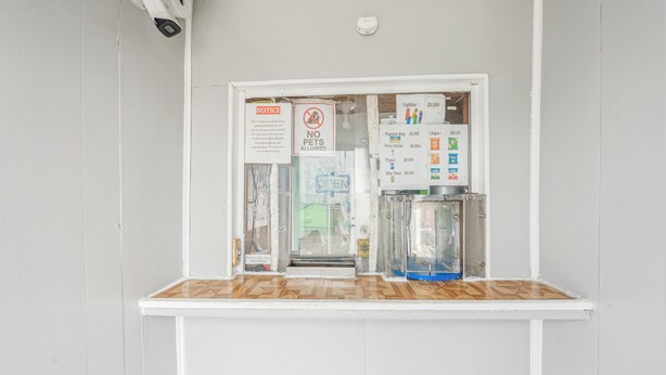 Een automaat met een bord waarop huisdieren verboden zijn, een mededeling en een prijslijst voor producten zoals zakken popcorn en waterflessen.