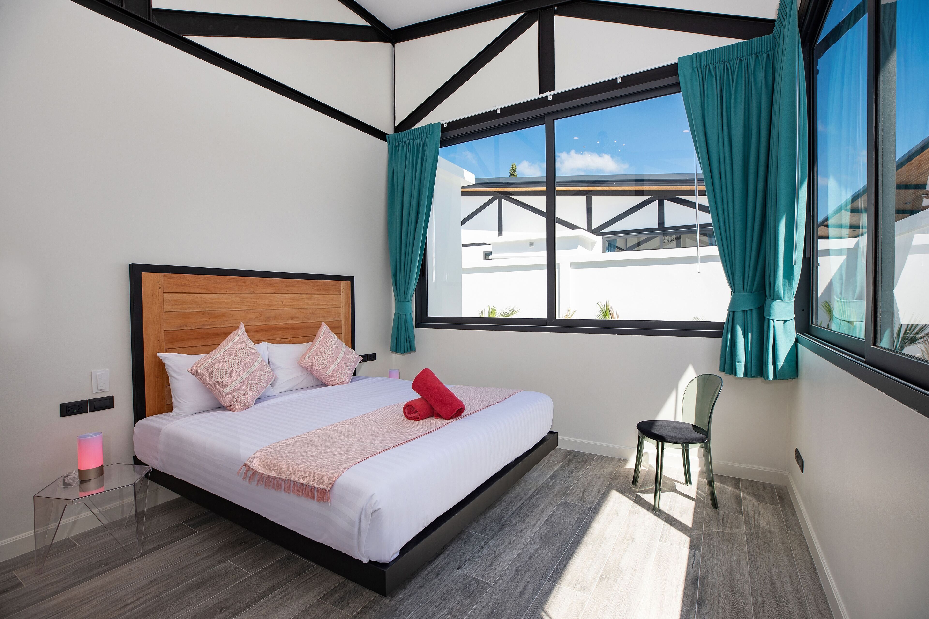 A modern hotel room with a large bed, a chair, and a view of the outside.