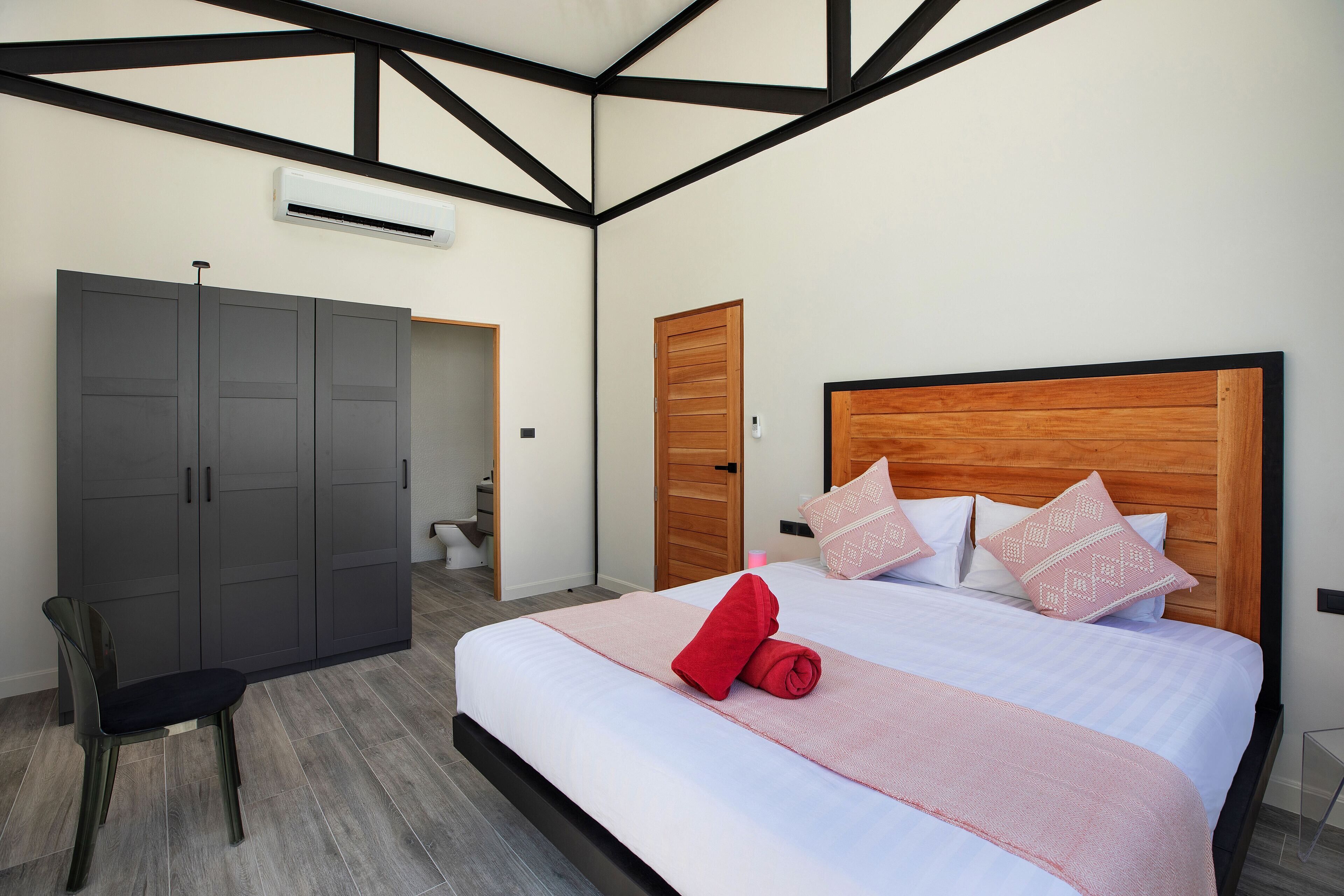 Een slaapkamer met een groot bed, een kledingkast en een stoel.