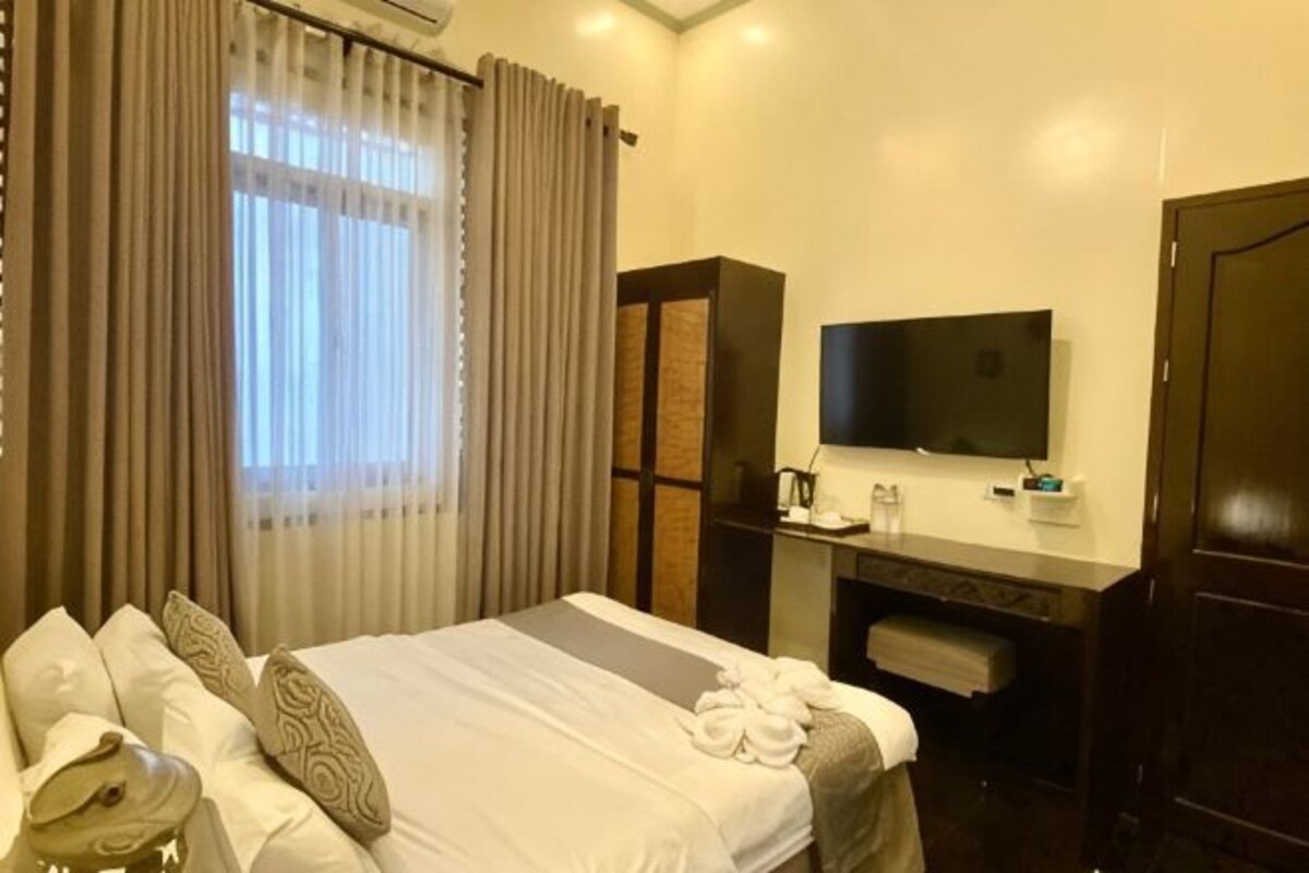 Una habitación de hotel con cama, escritorio, televisor y armario.