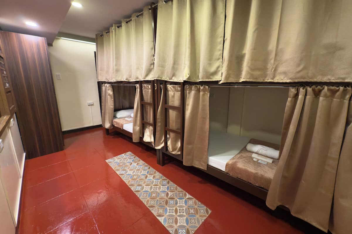 Una habitación con literas, cortinas color beige, una alfombra estampada y una puerta de madera.