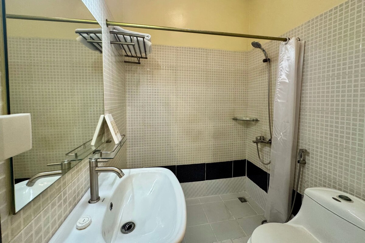 A bathroom with a white sink, a toilet, and a shower area.