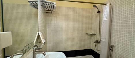 Un baño con lavamanos blanco, inodoro y zona de ducha.
