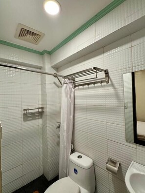 A small bathroom with white tiled walls, a shower curtain, a towel rack, a toilet, and a sink. - Park Avenue Boutique Hotel (Pasay)