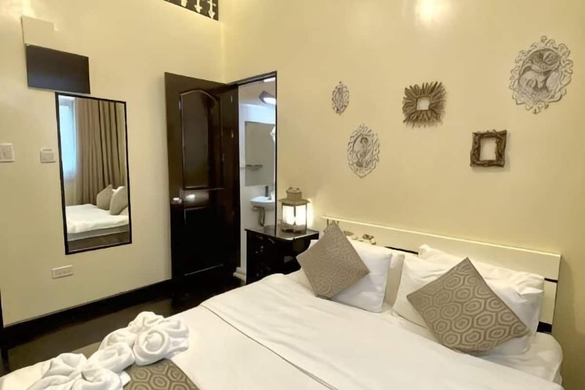 Habitación de hotel con cama, espejo, mesita de noche y decoración en la pared.