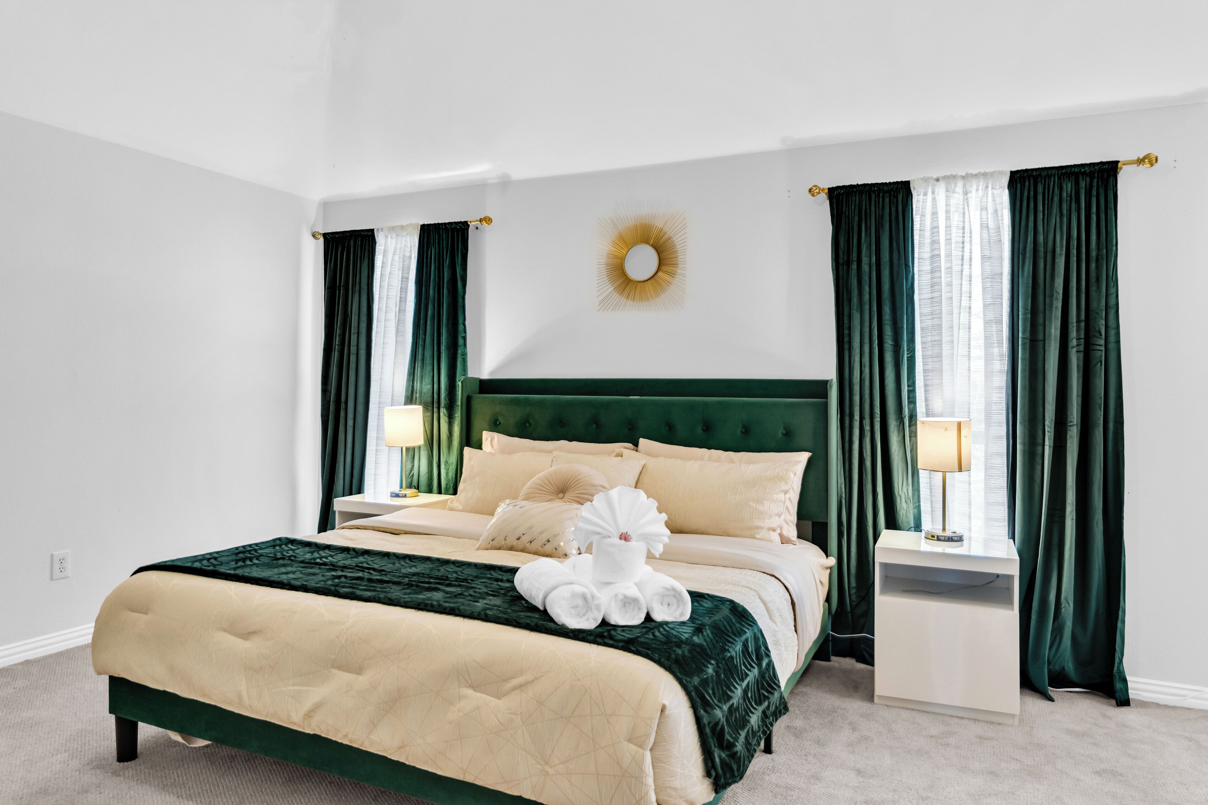 A neatly made bed with a green headboard, white bedding, and a decorative wall piece.