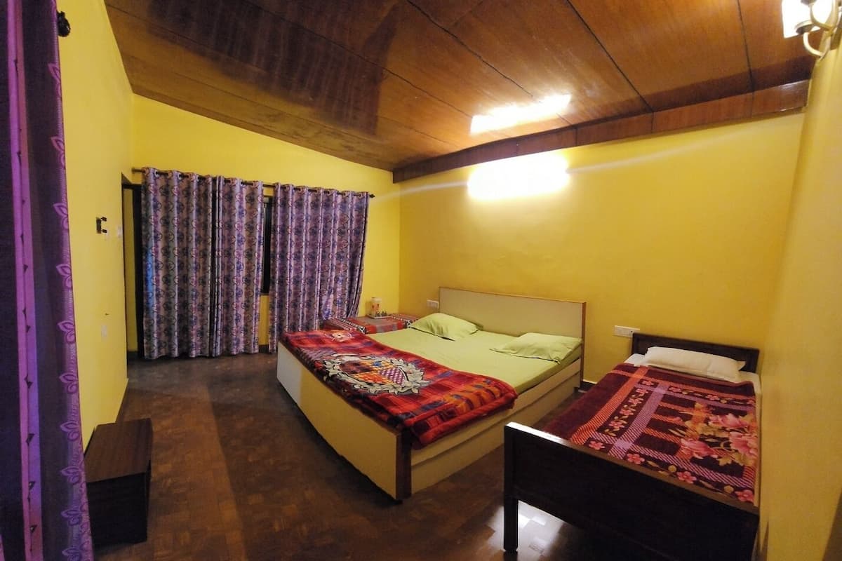 A room with two beds, wooden flooring, and a ceiling with exposed beams.
