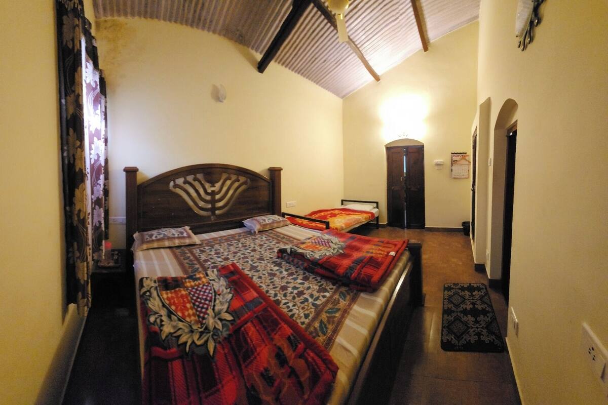A bedroom with a large bed, a wooden headboard, a nightstand, a door, and a wall-mounted calendar.