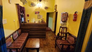 A narrow hallway with a wooden bench, a table, and two chairs. A staircase leads to another room. - Check Inn Today Resort (Coonoor)