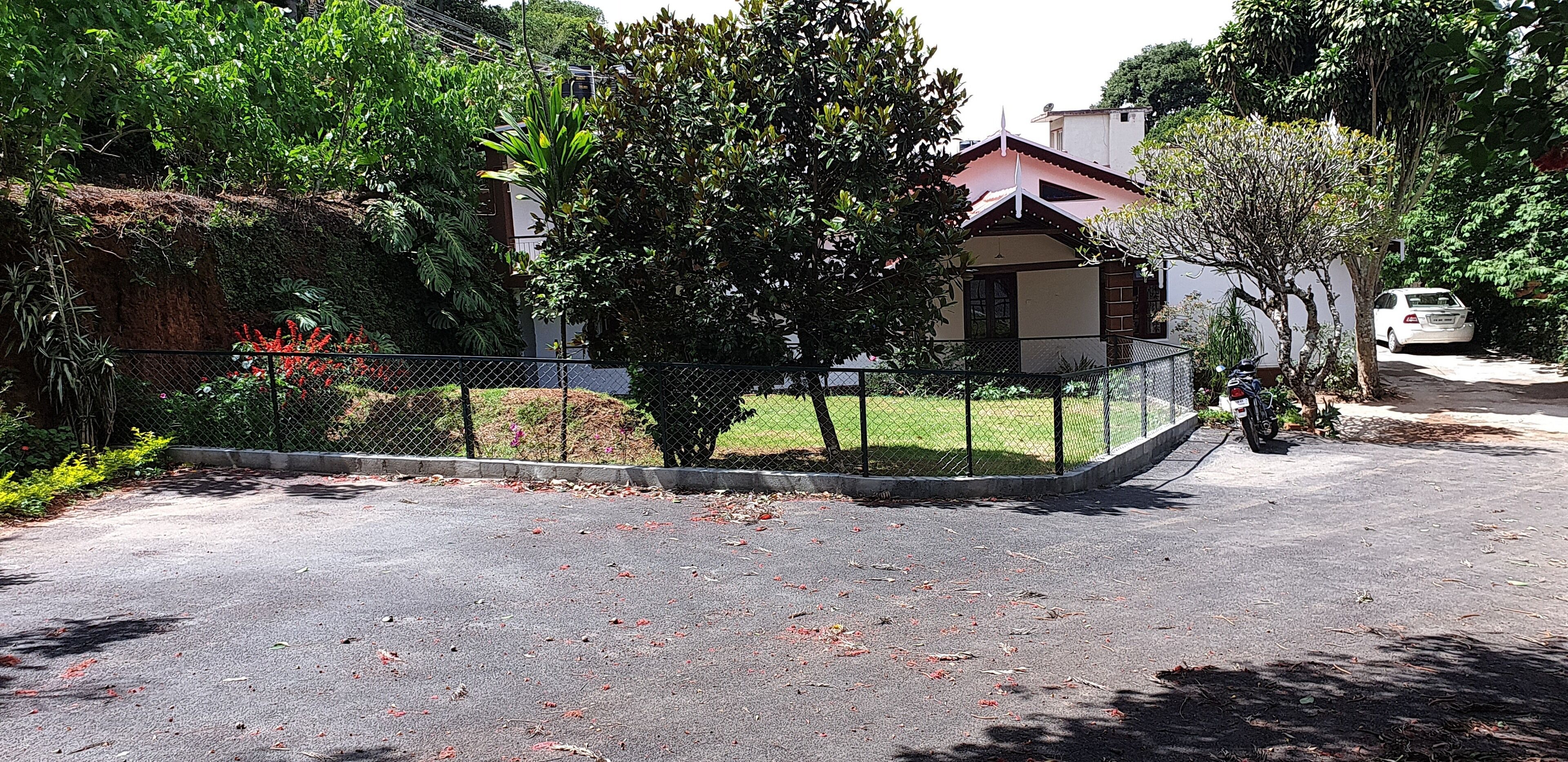 A residential area with a fenced yard, a parked motorcycle, and a house with a red roof.