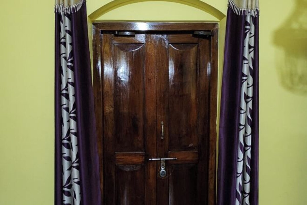 A wooden door with a metal handle and a lock, flanked by patterned curtains.