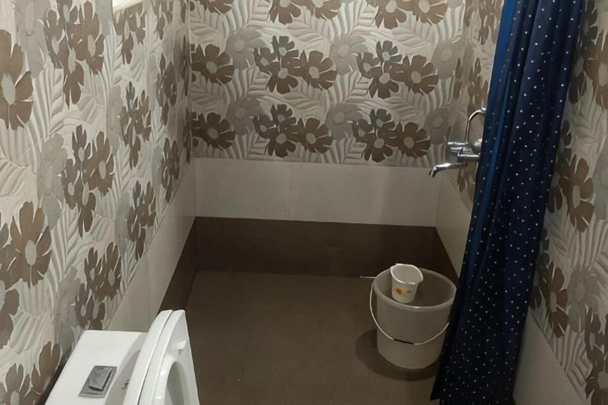 A bathroom with patterned wallpaper, a toilet, a bidet, and a small sink.