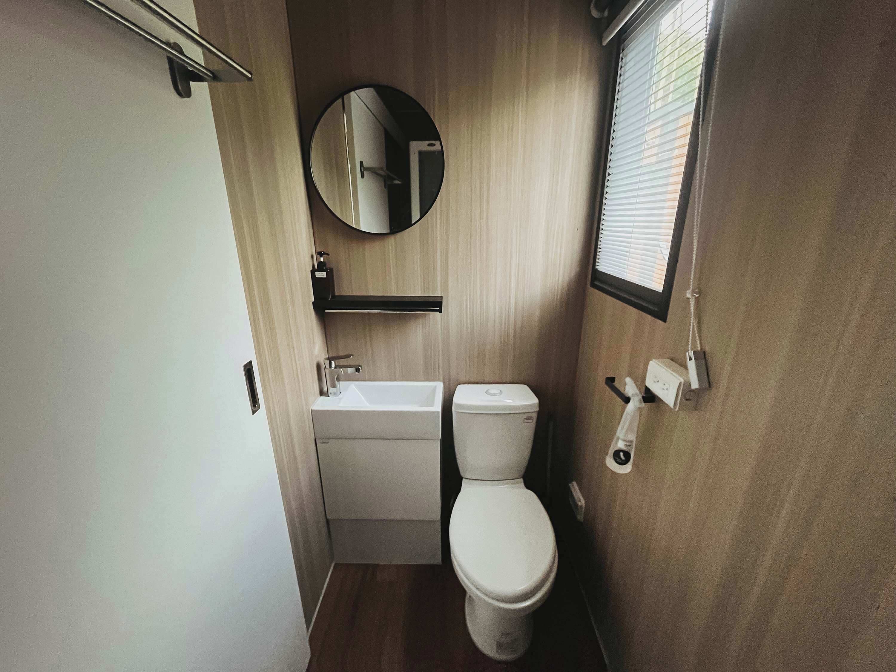 Un baño pequeño con inodoro, lavamanos y espejo.