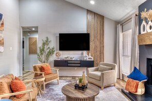 Un salon moderne doté d’un téléviseur à écran plat, d’une cheminée et d’un coin salon confortable.