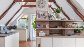 A kitchen with wooden beams, a clock, and a view to the outside.