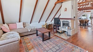 A loft-style living room with exposed wooden beams, a fireplace, a sofa, and a coffee table.