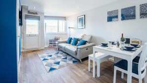 A modern living room with a sofa, dining table, and a geometric rug. - Sea View Chalet | Walk to Freshwater Beach (Pembrokeshire)