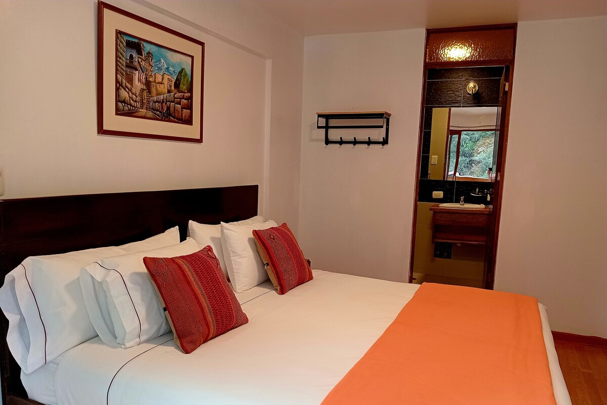 A neatly made bed with white and red bedding, a wooden headboard, and a framed picture on the wall.