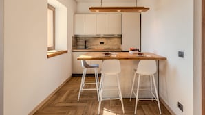 A compact kitchen with wooden countertops, white cabinets, and a small bar area with stools.