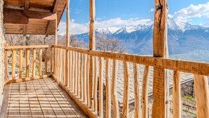 A wooden balcony with a view of snow-capped mountains.