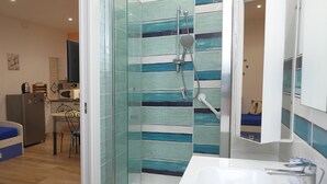 A modern bathroom with a glass shower enclosure, a white sink, and a mirror above it.