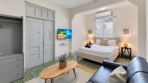 Ein Schlafzimmer mit Bett, Nachttischlampen, Fernseher, Kleiderschrank und einem kleinen Tisch mit Pflanze.