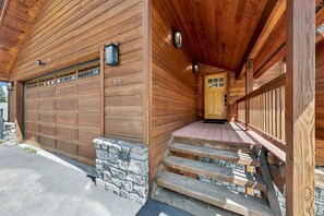 A wooden cabin with a garage, stone steps, and a wooden porch. - Beautiful Views, Game Room, EV Charger, Weber BBQ (Truckee)