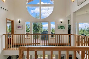 Ein geräumiger Innenraum mit hoher Decke, großen Fenstern und einem Holzbalkon.