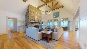 A spacious living room with a stone fireplace, wooden beams, and large windows. - Luxury Home. Blue Valley Views. Extraordinary Attention to Detail | Sevenoaks Cottage (Highlands)