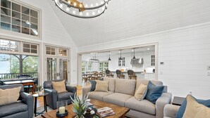 A spacious living room with a large sofa, a coffee table, and a dining area in the background. - Luxury Home. Blue Valley Views. Extraordinary Attention to Detail | Sevenoaks Cottage (Highlands)