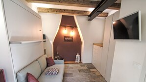 Een gezellige kamer met een bank, een televisie en een stenen vloer.