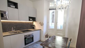 Een moderne keuken met een ingebouwde oven, een spoelbak en een eethoek met een tafel en stoelen.