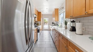 Una cocina moderna con electrodomésticos de acero inoxidable, armarios de madera y encimera blanca.
