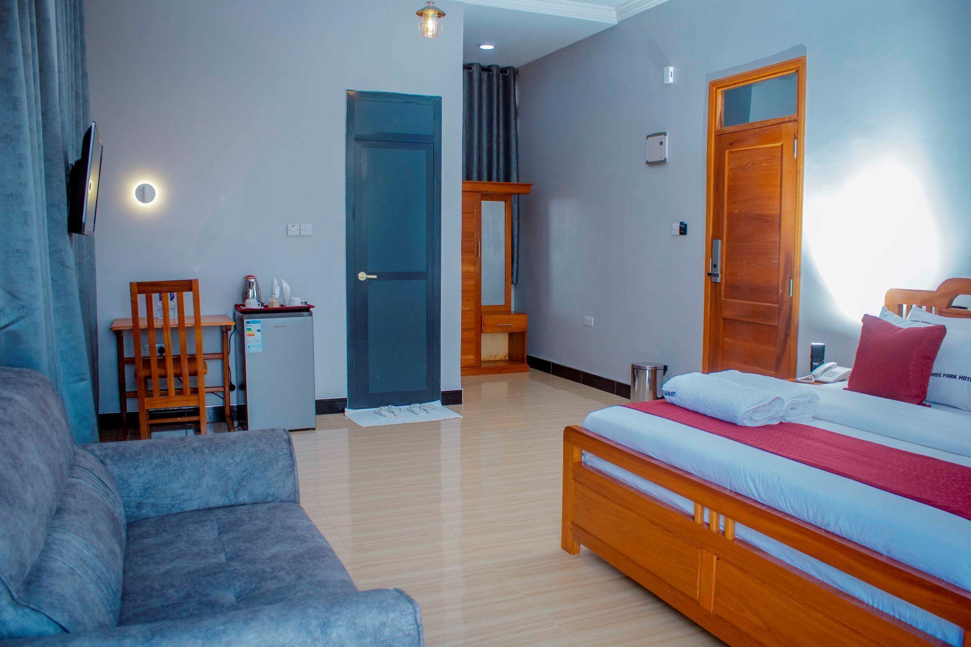 Une chambre d’hôtel avec un lit, un canapé, une petite table avec une bouilloire et une porte donnant sur une autre pièce.