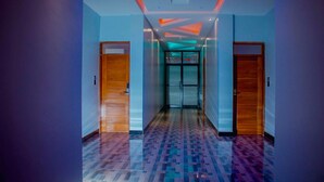 A modern hallway with patterned flooring, wooden doors, and a ceiling with recessed lighting and geometric designs. - Gombe Park Hotel (Morogoro)