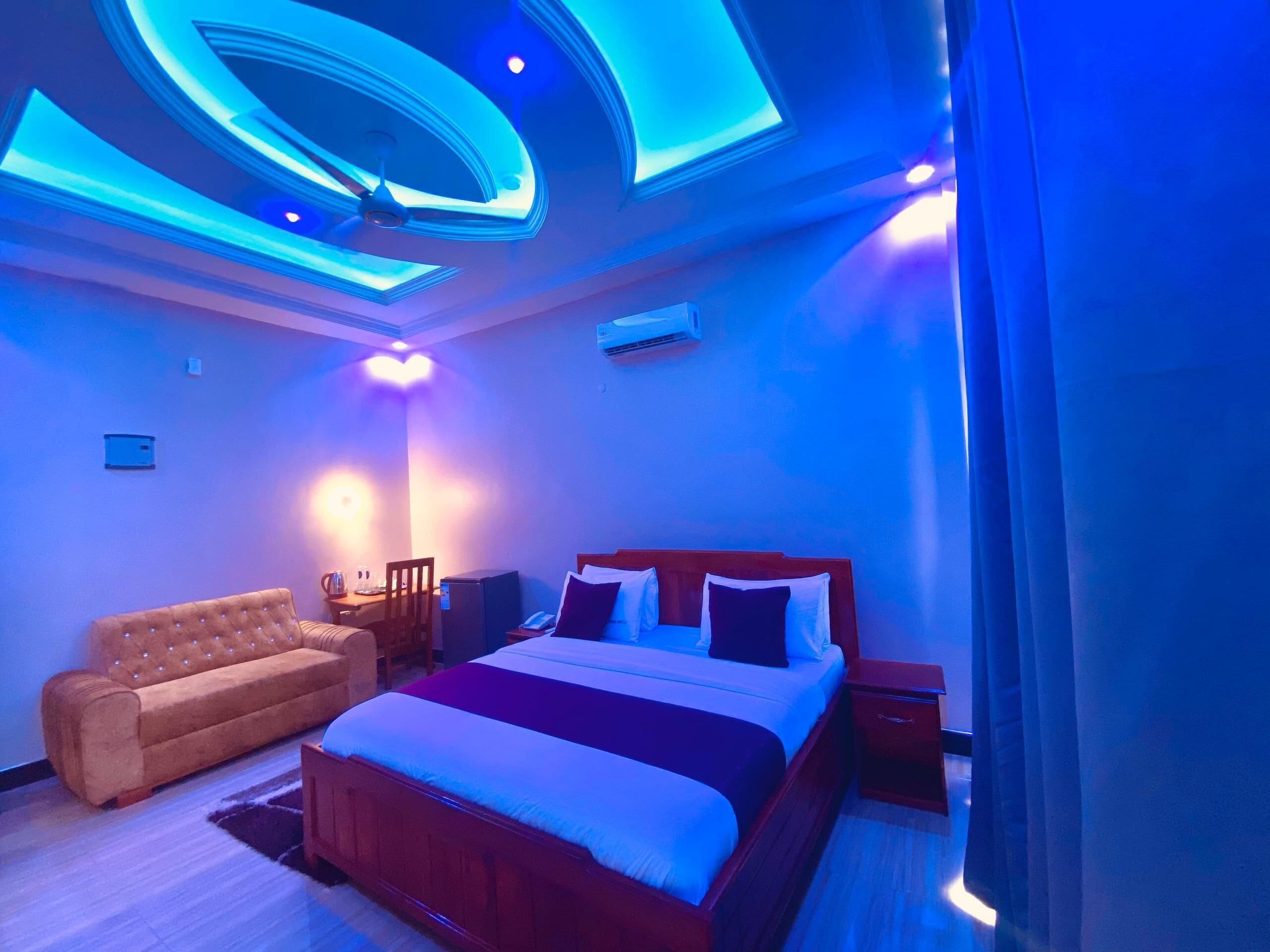 A modern bedroom with a large bed, a sofa, and a desk.