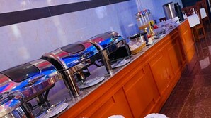 A buffet area with multiple self-service beverage dispensers and a variety of white teapots and cups arranged on a marble countertop. - Gombe Park Hotel (Morogoro)