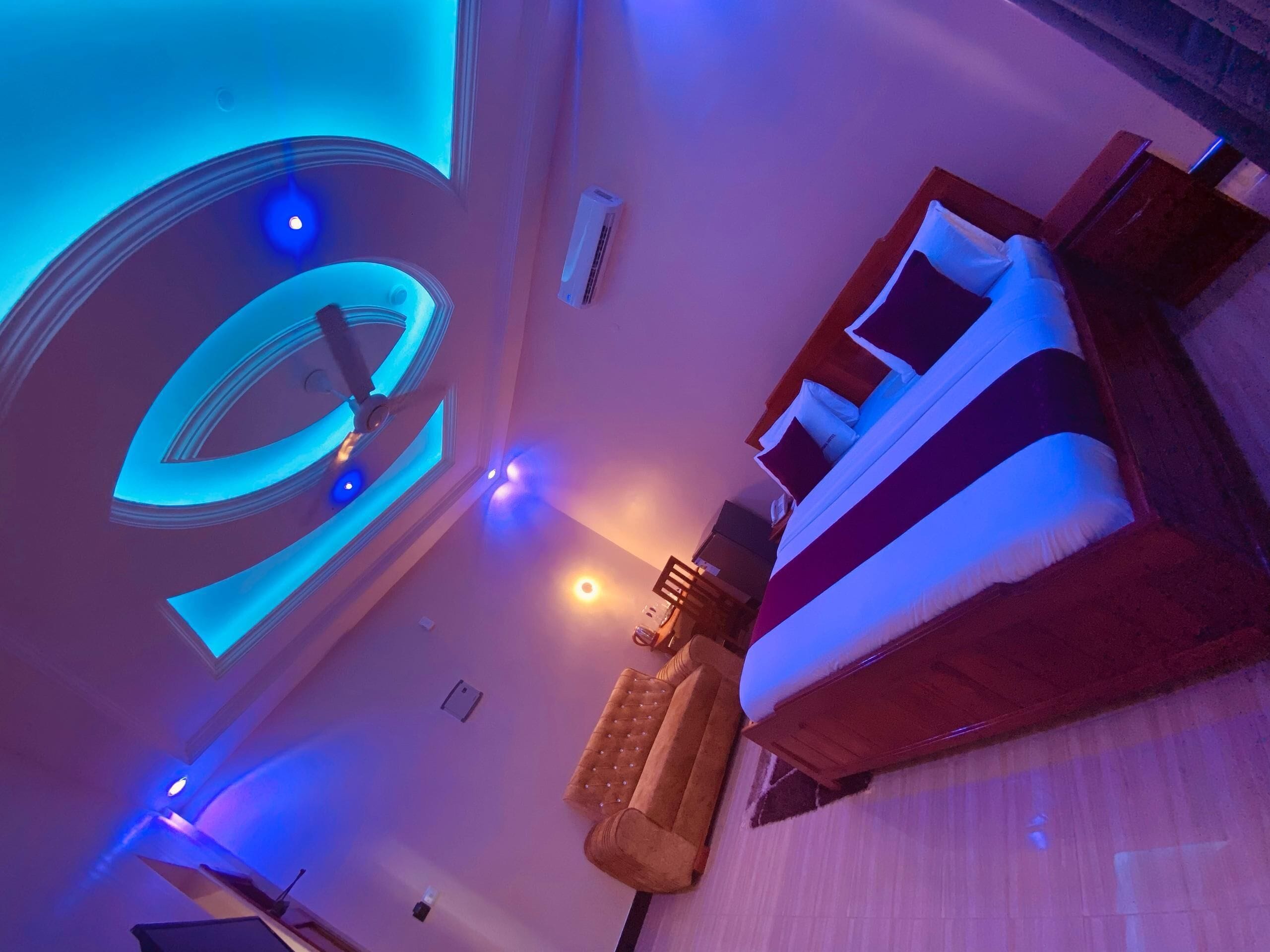 Une chambre à coucher moderne avec un grand lit, un canapé et un luminaire circulaire au plafond.